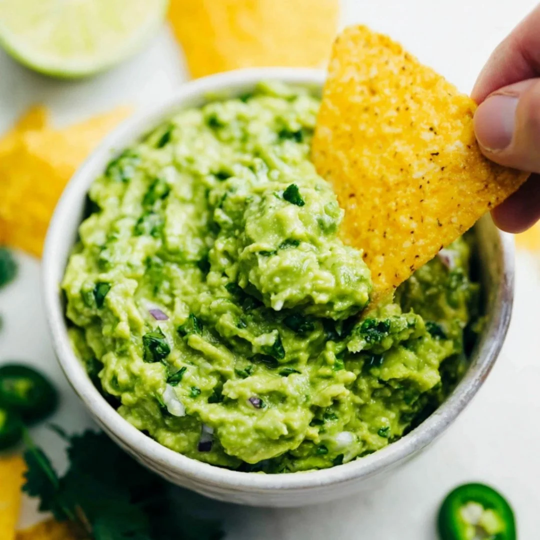 Fresh guacamole served with tortilla chips on a wooden table